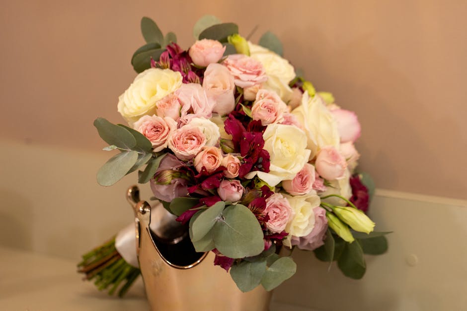 A dense arrangement of fresh roses in various shades of pink, white, and deep magenta, with some pale green hydrangea flowers interspersed. The bouquet is tightly packed, showcasing the ruffled petals